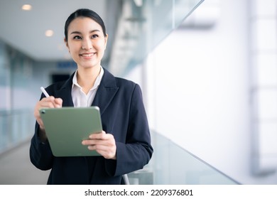 Asian Business Woman Holding A Tablet Looking Away , Smart Business Concept.