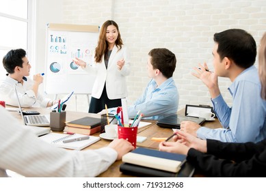 Asian business woman leader in a meeting with her multi-ethnic colleagues at the office presenting sales data or forecast for a project - Powered by Shutterstock