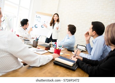 Asian Business Woman Leader Presenting Work To Mixed Race Colleagues In The Meeting