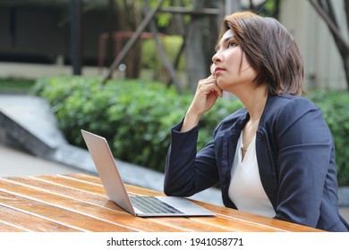 asian business woman look around for inspiration of working on public park for get good idea with oudoor environtment with laptop and wireless internet technology