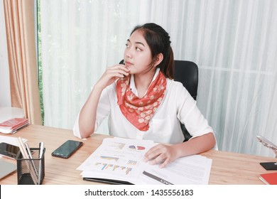 Asian Business Woman With Messy Desk In Office, She Is Absent-minded Forgets Things And Does Not Pay Attention To Job. Employee Officer Work At The Workplace, Feeling Bored And Can’t Focus On Work.