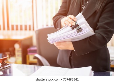 Asiatische Büroangestellte mit Sitz in Asien verfassen Dokumente mit unvollständigen Dokumenten auf dem Schreibtisch, Papierstapel, Dokumentenverwaltung, Geschäftsfrau, die Dokumente prüft