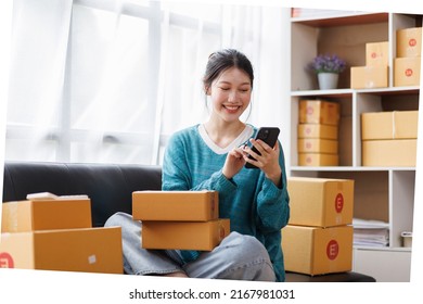 Asian Business Woman On Sofa Using A Laptop Computer Checking Customer Order Online Shipping Boxes At Home. Starting SME Small Business Entrepreneur Freelance. Online Business, SME Work Home Concept.