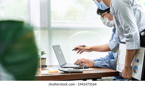 Asian business woman pointing on laptop screen to share idea about new project business to partner while wearing protective face mask to protect coronavirus and brainstorming together - Powered by Shutterstock