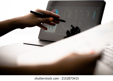 Asian Business Woman Reviewing Data In Financial Charts And Graphs With Tablet. Accounting