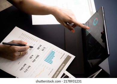 Asian Business Woman Reviewing Data In Financial Charts And Graphs With Tablet. Accounting