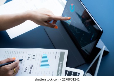 Asian Business Woman Reviewing Data In Financial Charts And Graphs With Tablet. Accounting