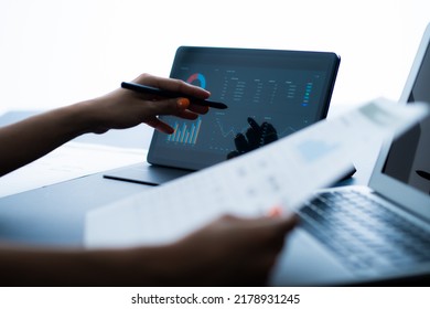 Asian Business Woman Reviewing Data In Financial Charts And Graphs With Tablet. Accounting