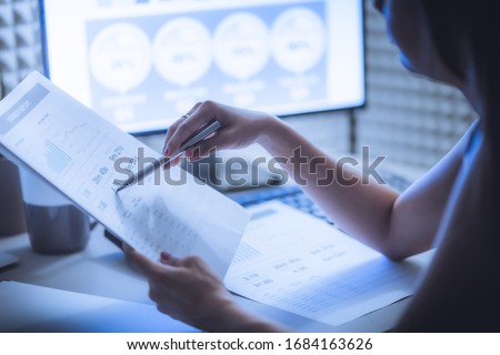 Asian business woman reviewing data in financial charts and graphs. Accounting