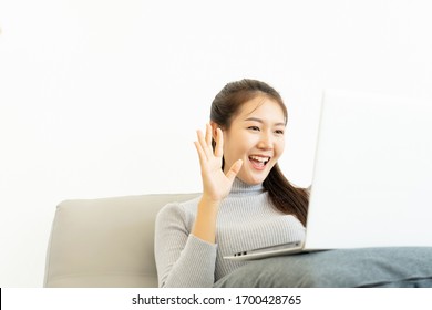 Asian Business Woman Show Hand Symbol Say Hello And Using Laptop Computer For Zoom Video Call Conference Working From Home During Infectious Corona Virus Or Covid-19 Spread