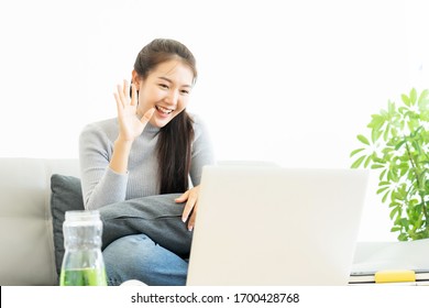 Asian Business Woman Show Hand Symbol Say Hello And Using Laptop Computer For Zoom Video Call Conference Working From Home During Infectious Corona Virus Or Covid-19 Spread