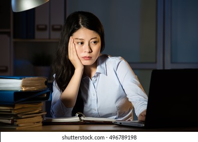 Asian Business Woman Sitting At Desk Sleepy Working Overtime Late Night. Indoors Office Background