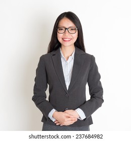 Asian Business Woman Smiling At Camera, Standing On Plain Background.