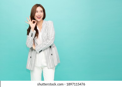 Asian business woman smiling and showing OK sign isolated on green background - Shutterstock ID 1897115476