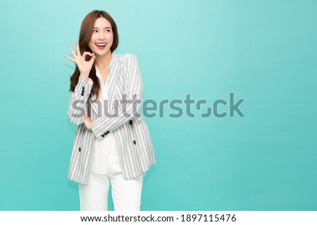 Asian business woman smiling and showing OK sign isolated on green background