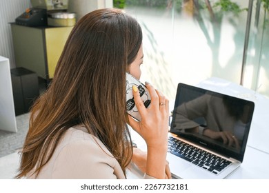 Asian business woman talking conferences team and clients on phone while working using laptop notebook, co working space, cafe, flexible working, new normal, online business. Work from anywhere. - Powered by Shutterstock