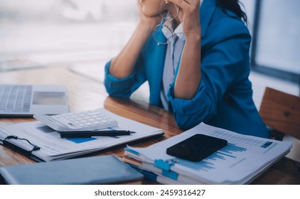 Asian Business woman using calculator and laptop for doing math finance on an office desk, tax, report, accounting, statistics, and analytical research concept - Powered by Shutterstock