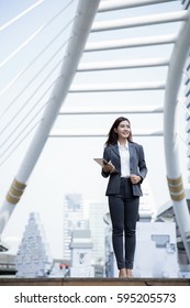 Asian Business Woman Walking On Street Holding Tablet And Smiling