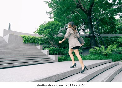 Asian business woman walking to work diligently and briskly in morning in a big city. female in a business suit, dressed in a smart suit, runs to work during rush hour in corridors and stairs. - Powered by Shutterstock