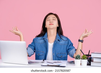 Asian Business Woman Wear Casual Shirt Sit Work At White Office Desk With Pc Laptop Isolated On Pastel Pink Background Studio. She Is Hold Hands In Yoga Om Gesture Relax Meditate Try To Calm Down.