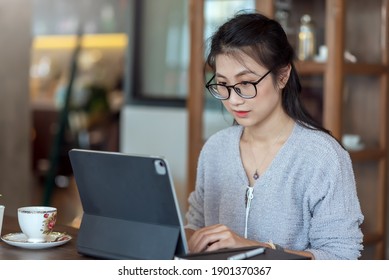 Asian business woman with working with a digital tablet and coffee at home.