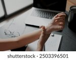 An asian business woman working for a long time and typing the computer, so her wrist is hurt and she is massaging her hurt wrist by another hand and this is a kind of office syndrome.