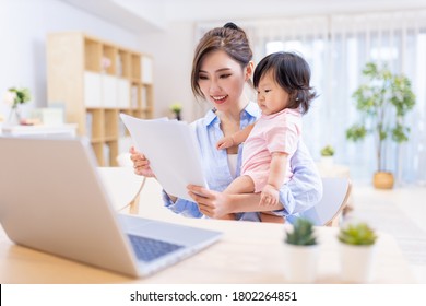 asian business woman works from home by laptop and takes care of her daughter - Powered by Shutterstock