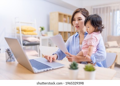 Asian Business Woman Works From Home By Laptop And Takes Care Of Her Daughter