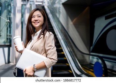 Asian Business Women Going To Work In The Morning On The Subway She Was Smiling In Her Hand Holding A Laptop And Hot Coffee.