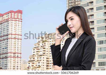 Asian Business women using phone mobile touch screen smiling looking communication technology call business coordinate real estate clients. social network city tower background