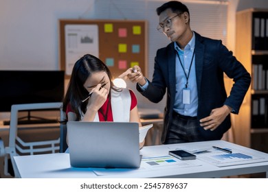 Asian businessman blaming, scolding, reprimanding stressed businesswoman working overtime in office at night - Powered by Shutterstock