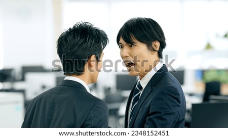 Asian businessman boss yelling at subordinate in modern office.