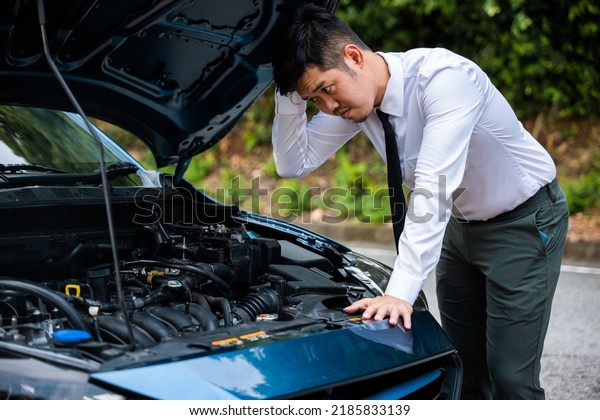 Asian\
businessman car broken breakdown, young stressed man having trouble\
car failure problem looking in frustration at failed engine in the\
morning, accident on road outdoor, late for\
work
