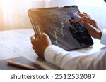 Asian businessman checking stock market data, Stock market application for iPad, Analyzing stock market data on desktop, Young businessman with stock market chart background