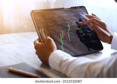 Asian businessman checking stock market data, Stock market application for iPad, Analyzing stock market data on desktop, Young businessman with stock market chart background