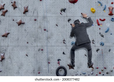 Asian Businessman Climb The Rock Climbing Wall At Outdoor