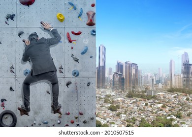 Asian Businessman Climb The Rock Climbing Wall With Blue Sky Background