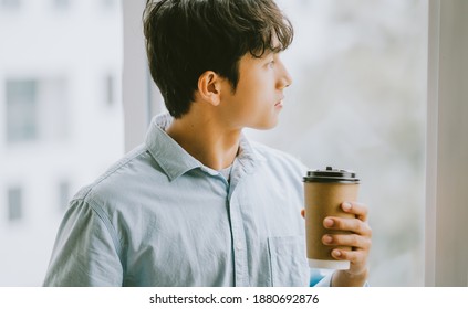 Asian Businessman Is Drinking Coffee By The Window
