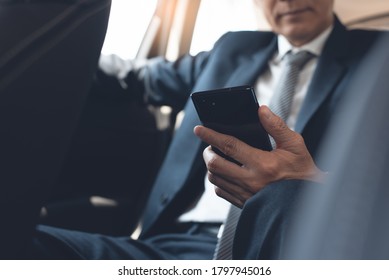 Asian Businessman, Executive Manager Reading Message Or Morning News Via Mobile Smart Phone Application Inside A Car On Backseat, Business Concept. Corporate Man, Lawyer Going To Workplace, Close Up