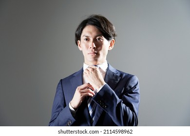 Asian businessman fastening his tie