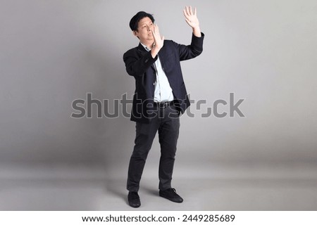 The Asian Businessman with formal dressed with gesture of stop, forbid, refusing on the gray background.