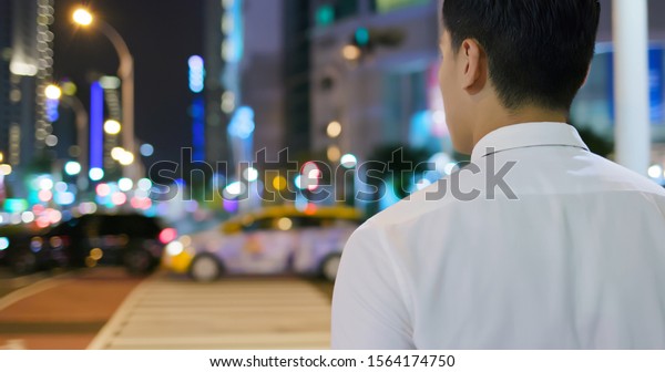 asian businessman get off work and walk on the\
street in the evening