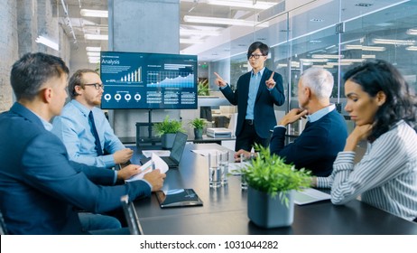 Asian Businessman Gives Report/ Presentation to His Business Colleagues, Pointing at the Results Showing Statistics, Pie Charts and Company's Growth On Wall TV Screen. - Shutterstock ID 1031044282