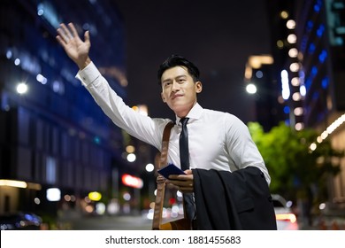 asian businessman hail a taxi on road to commute in the city at night - Powered by Shutterstock