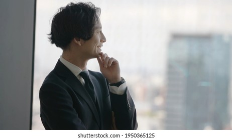 asian businessman looking out of window - Shutterstock ID 1950365125