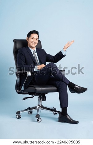 Asian businessman male portrait sitting on chair and isolated on blue background
