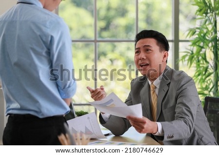 Asian businessman manager in suit holding paperwork and strong talking for young employee with anger and serious gesture look like he comments as disagree or unacceptable for his project work