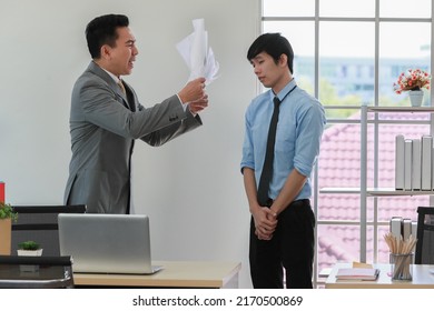 Asian Businessman Manager In Suit Throwing Paperwork Into Air And Blaming For Young Employee With Anger And Serious Gesture. Office Work Problem And Job Quality Conflict Concept