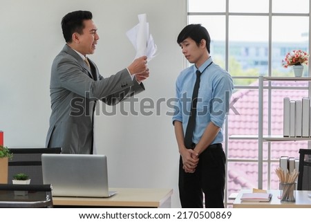 Asian businessman manager in suit throwing paperwork into air and blaming for young employee with anger and serious gesture. Office work problem and job quality conflict concept