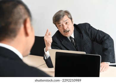 Asian businessman in a middle-aged suit who gets angry at an employee